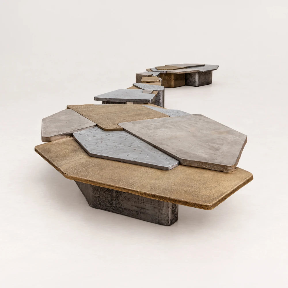 Close perspective of the Scorpio set of four coffee tables by Eva Szumilas, highlighting layered gold-toned and silver-toned tops on the nearest table.